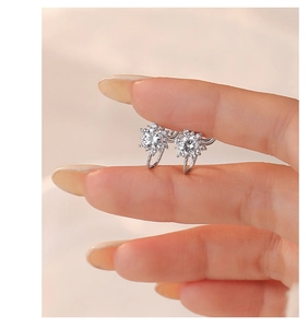 Macro view of tiny silver snowflake ear clips with sparkling zircons held between fingers