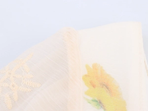 Makro-Detail von französischen Blumenstickereien auf einem Baumwoll-Leinen-Kleid