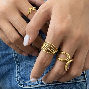 Macro view of gold geometric layered rings worn against a blue denim background