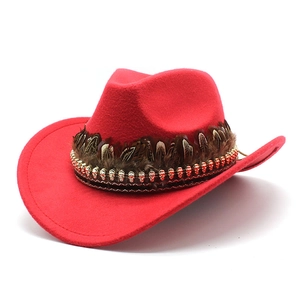 Detail of red wool cowboy hat with brown feathers and golden skull beads decoration