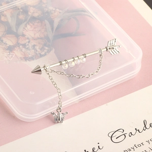Detailed view of silver industrial barbell earring with butterfly pendant and arrow shaft