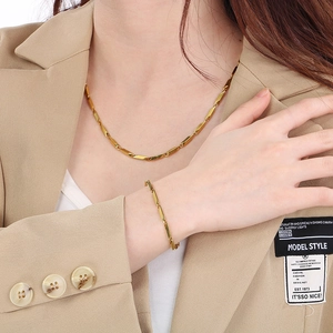 Detail of a gold stainless steel link chain necklace and bracelet set on a beige blazer