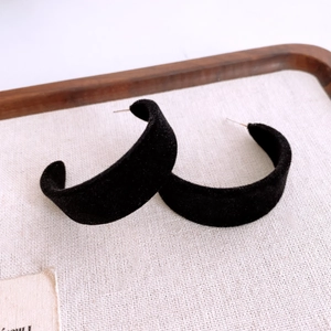 Détail de boucles d'oreilles noires en forme de C floquées avec texture en velours