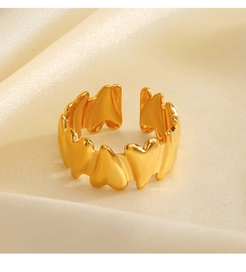 Close-up of a gold heart-shaped chain ring on soft beige silk fabric background
