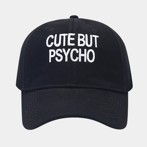 Detail of embroidered 'CUTE BUT PSYCHO' text on black cotton baseball cap with neat stitching
