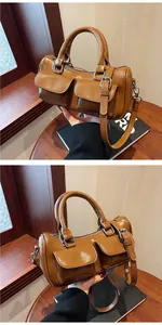 Detail view of brown glossy saddle bag with double front pockets and silver buckles