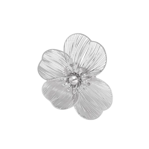 Close-up of silver metal flower jewelry with brushed texture and central bead detail