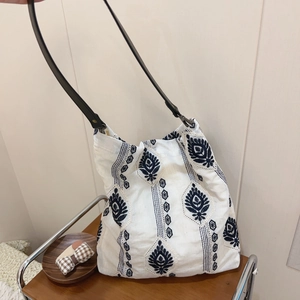 Detail of ethnic floral embroidery on a white cotton linen tote bag with black strap