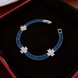 Detail of silver bracelet featuring deep blue gems and white zircon flower charms