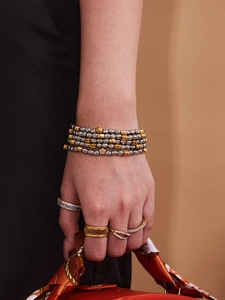 Detail of layered gold and silver textured bead bracelet with zircon flower accents