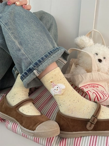 Detail of yellow speckled cotton mid-calf socks with white puppy embroidery on a model