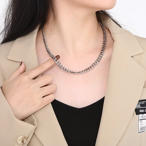 Chic silver titanium steel Cuban link chain necklace worn by a female model in a blazer