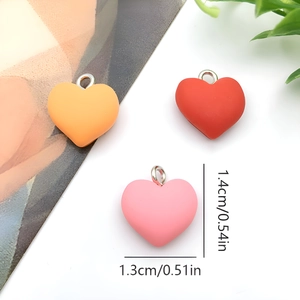 Three colorful heart-shaped resin pendants in orange, red, and pink with size dimensions