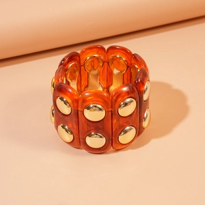 Detail of amber resin segments with gold metal rivets on a vintage style chunky bangle