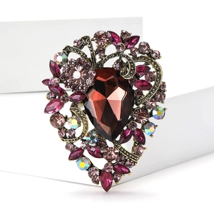 Macro shot of vintage heart brooch with a pear-shaped brown gem and multi-color rhinestones