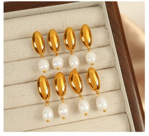 Detailed view of four pairs of 18K gold teardrop pearl earrings on a beige velvet tray