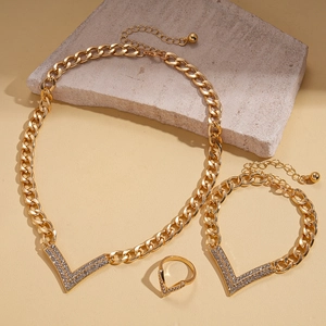 Detailed view of 3-piece gold jewelry set with V-shaped pavé rhinestones on beige stone