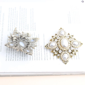 Vintage gold diamond shaped brooch with large pearls and rhinestones on book background