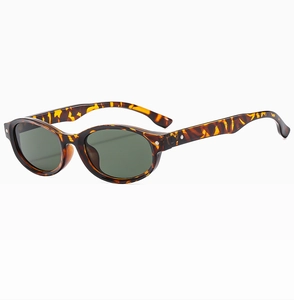 Détail de lunettes de soleil ovales en écaille avec verres verts et rivets argentés