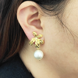 Elegant gold leaf earrings with white pearls shown on a model for a minimalist nature style