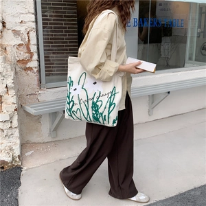 Detail of chamomile print canvas tote bag featuring stylish Don't ever change typography