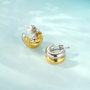 Close-up of two-tone C-shaped hoop earrings with gold and silver layered metal finish