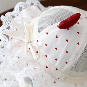 Détails de la dentelle blanche et des motifs de cœurs rouges sur le chapeau d'été pour bébé