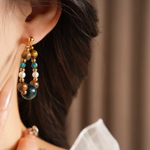 Gros plan d'une boucle d'oreille vintage en œil de tigre et perle sur un mannequin