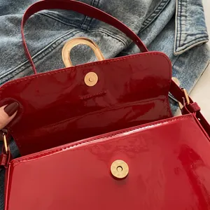 Detailed macro view of the metal magnetic closure on a red patent leather handbag