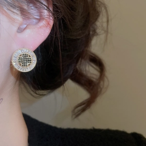 Close-up of vintage round stud earrings featuring gold plating and black zircon inlay