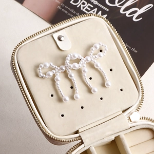 Detail view of a cream jewelry box with a handmade pearl bow brooch and inner compartments