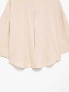 Détail d'une chemise en lin beige montrant l'ourlet incurvé et la texture du tissu tissé