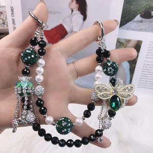 Macro detail of beaded phone chain with a green gemstone bee pendant and silver clasp