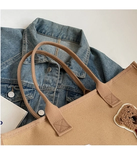 Detailed shot of khaki canvas tote bag featuring a cute fuzzy brown 3D bear patch