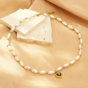 Detail of beaded necklace with faux pearls and a black heart pendant on satin