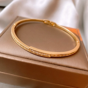 Nahaufnahme eines vergoldeten Armreifs mit Zirkonia auf einer Schmuck-Geschenkbox