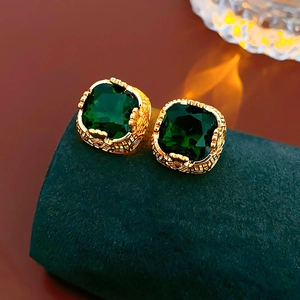 Dettaglio di orecchini vintage dorati con zirconi verde smeraldo a taglio quadrato