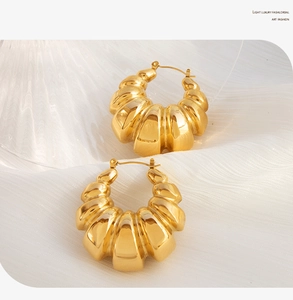 Macro detail of chunky gold croissant hoop earrings with polished ribbed texture