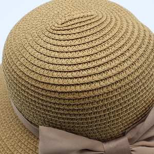 Gros plan sur le tissage en spirale et le nœud en satin du chapeau de paille