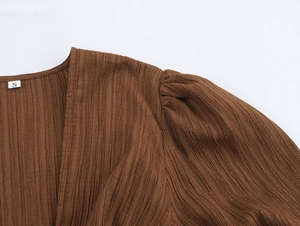 Detail of brown pleated fabric texture and collar stitching on a beach style top