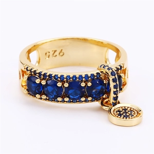 Detail of 925 silver gold ring with blue zircon stones and dangling round charm pendant