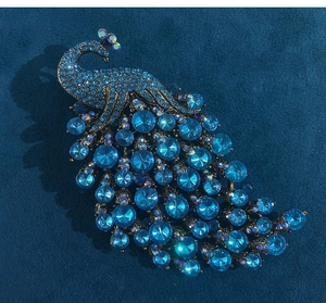 Close-up of vintage peacock brooch with blue crystals on dark navy velvet background
