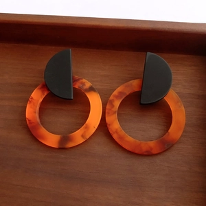 Detail view of resin drop earrings with black matte stud and amber tortoise shell circle