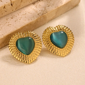 Detail of gold heart earrings featuring green cat eye stones and textured metal edges