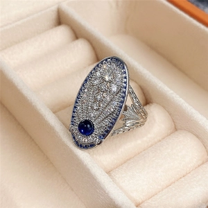 Detalle de anillo estilo palacio vintage con circón azul y banda de plata grabada