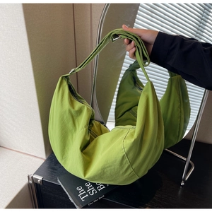 Detail of green nylon crossbody bag showing its large capacity and soft pleated texture