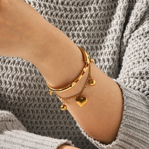 Primer plano de pulsera de doble capa de oro de 18k con dije de corazón sobre punto