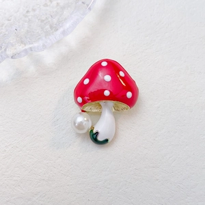 Détail de la broche champignon rouge avec points blancs et perle délicate ornée