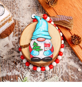 Detailed view of hand-painted wooden Christmas gnome ornament on natural wood with pine cones