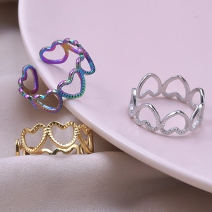 Detailed view of heart-shaped hollow rings in colorful, gold, and silver finishes on silk